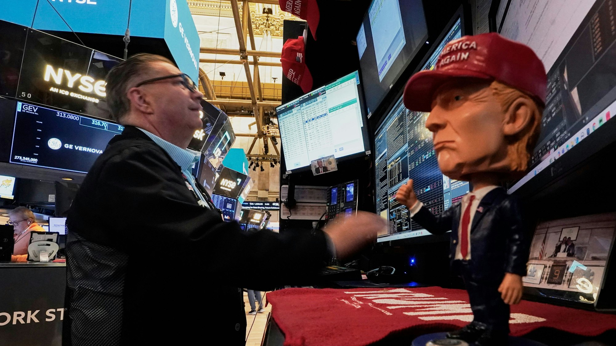 New York: Eine Donald-Trump-Wackelfigur steht auf dem Tresen, während der Händler Jonathan Mueller auf dem Parkett der New Yorker Börse arbeitet.