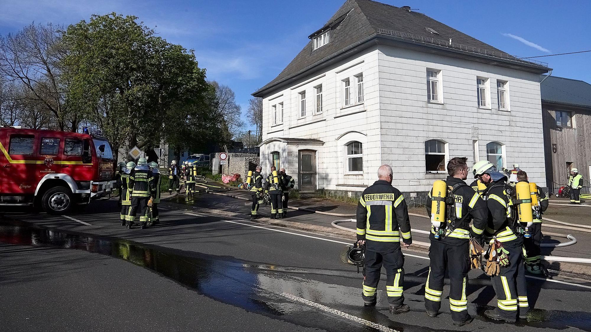 Feuerwehrleute stehen vor einem Haus in Hellenthal-Kehr, in dem es gebrannt hat.