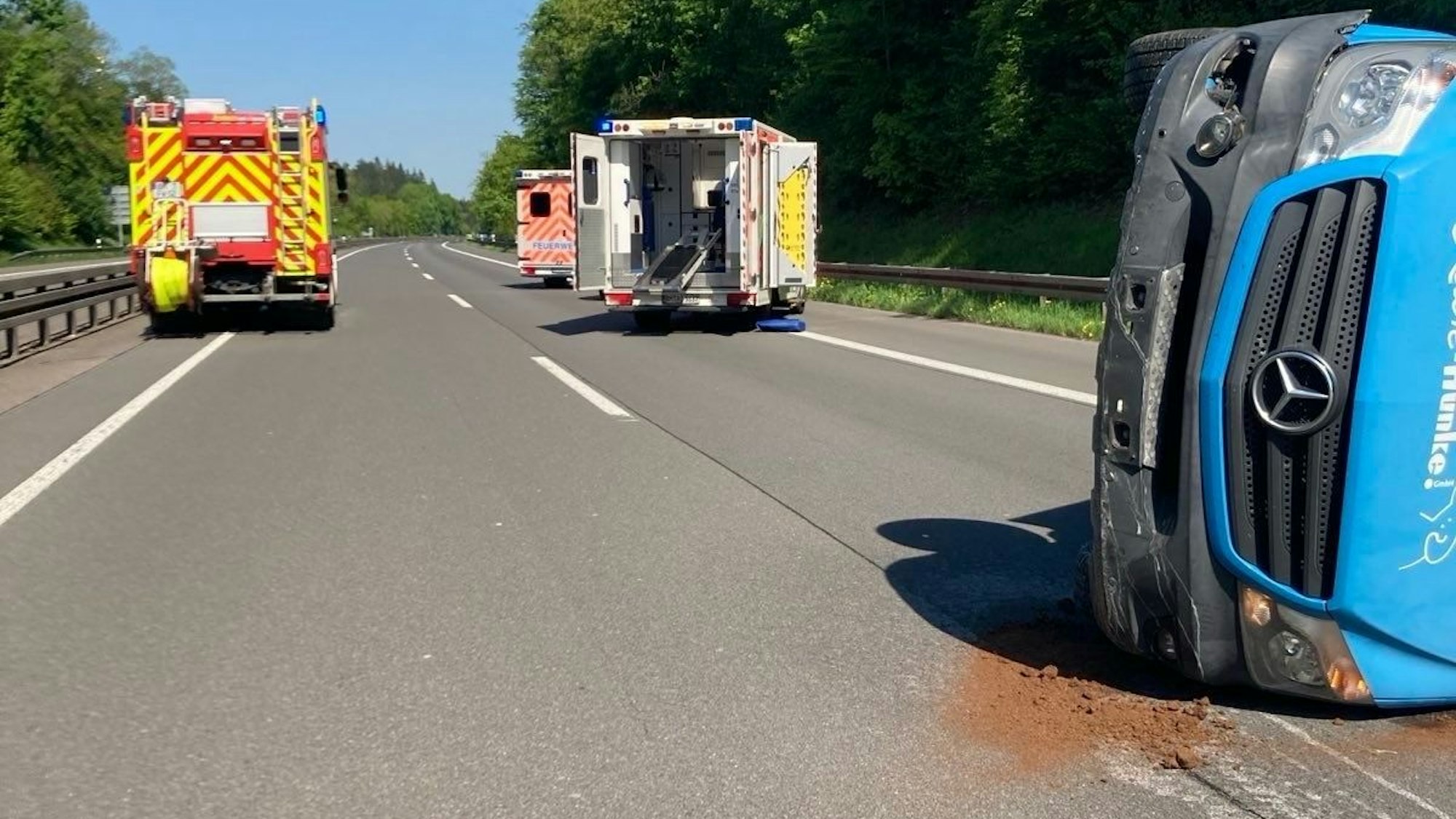 Auf der Autobahn liegt ein Transporter auf der Seite, dahinter stehe zwei Krankenwagen und ein Feuerwehrfahrzeug.