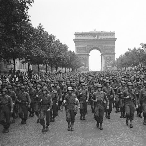 Amerikanische Truppen marschieren nach der Befreiung der französischen Hauptstadt über den Champs Elysees, im Hintergrund ist der Arc de Triomphe zu sehen.