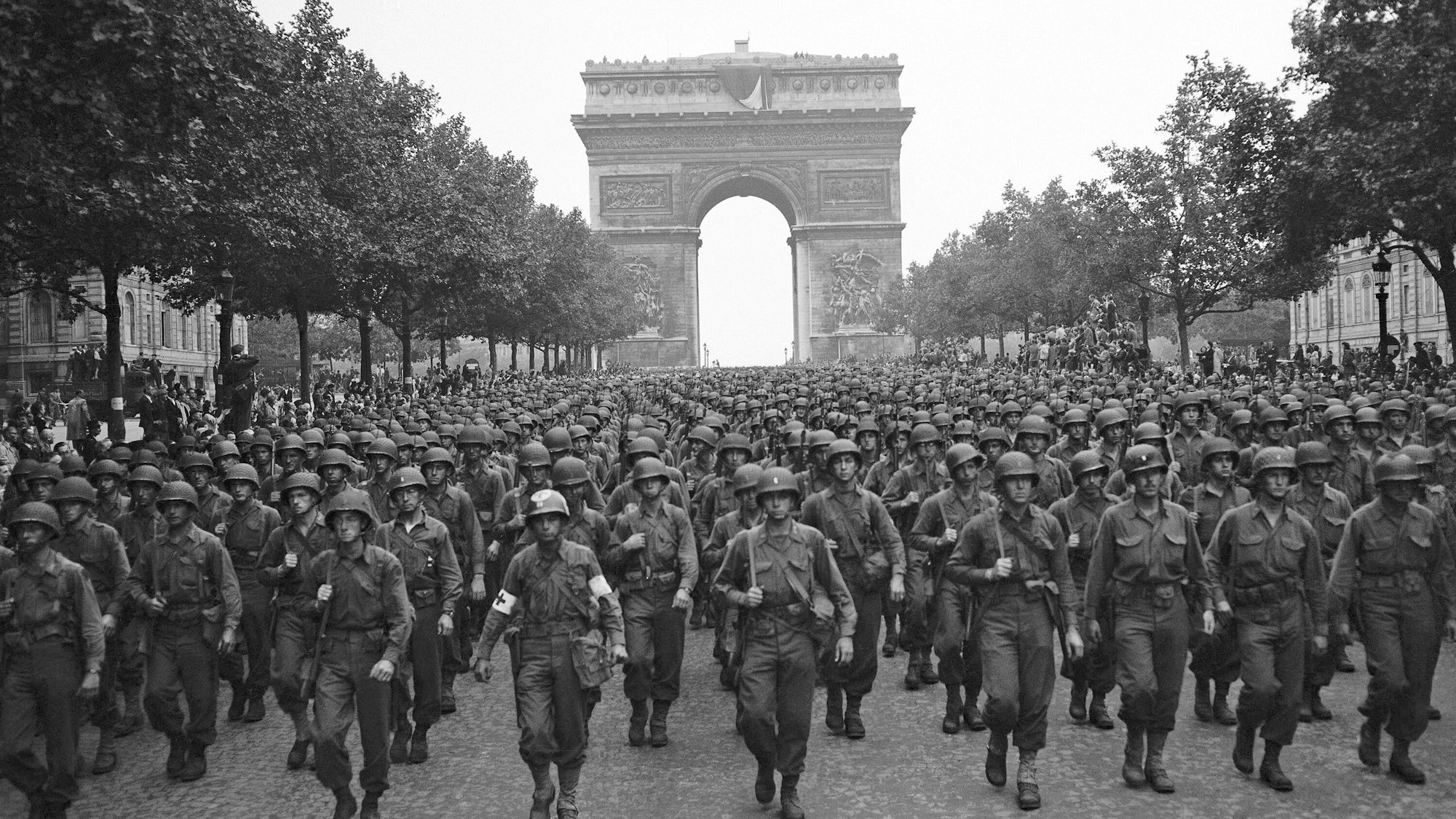 Amerikanische Truppen marschieren nach der Befreiung der französischen Hauptstadt über den Champs Elysees, im Hintergrund ist der Arc de Triomphe zu sehen.