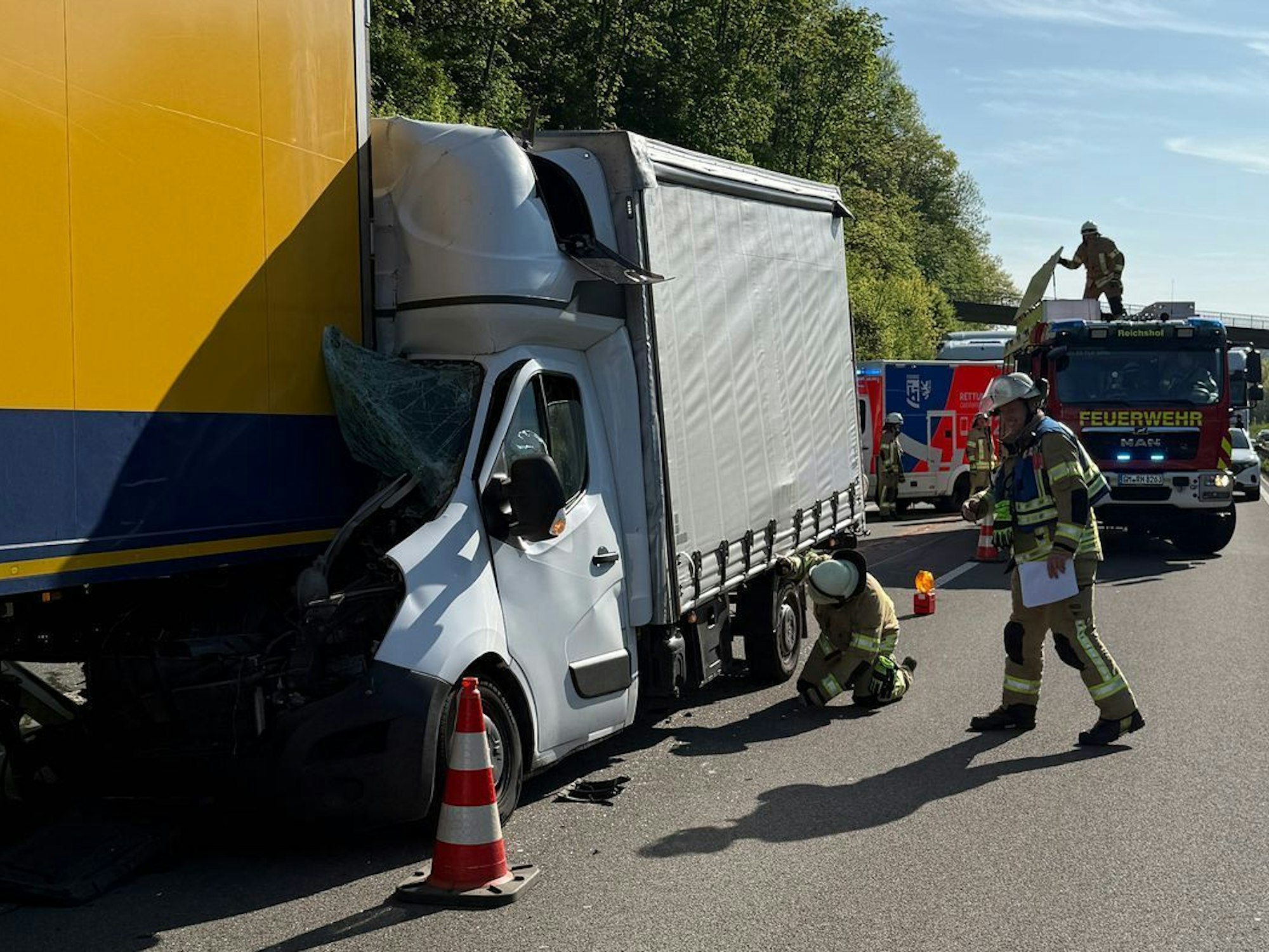 Feuerwehrleute neben den beschädigten Lkw.