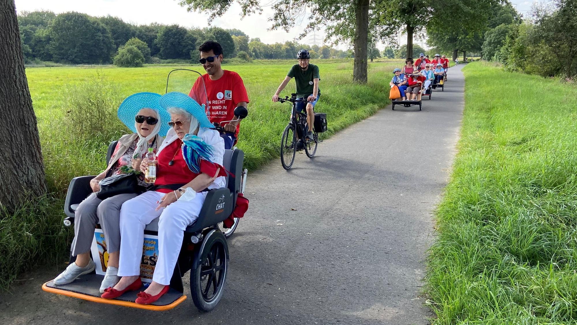Ehrenamtliche fahren Seniorinnen und Senioren für den Verein „Radeln ohne Alter“ durch die Natur.