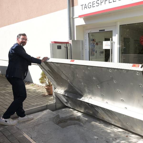 Vor der Tagespflege des Wöllner-Stifts in Rösrath-Hoffnungsthal zeigt Geschäftsführer Michael Heine, wie eine Edelstahl-Wand im Fall von Hochwasser automatisch hochgefahren wird.