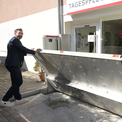 Vor der Tagespflege des Wöllner-Stifts in Rösrath-Hoffnungsthal zeigt Geschäftsführer Michael Heine, wie eine Edelstahl-Wand im Fall von Hochwasser automatisch hochgefahren wird.