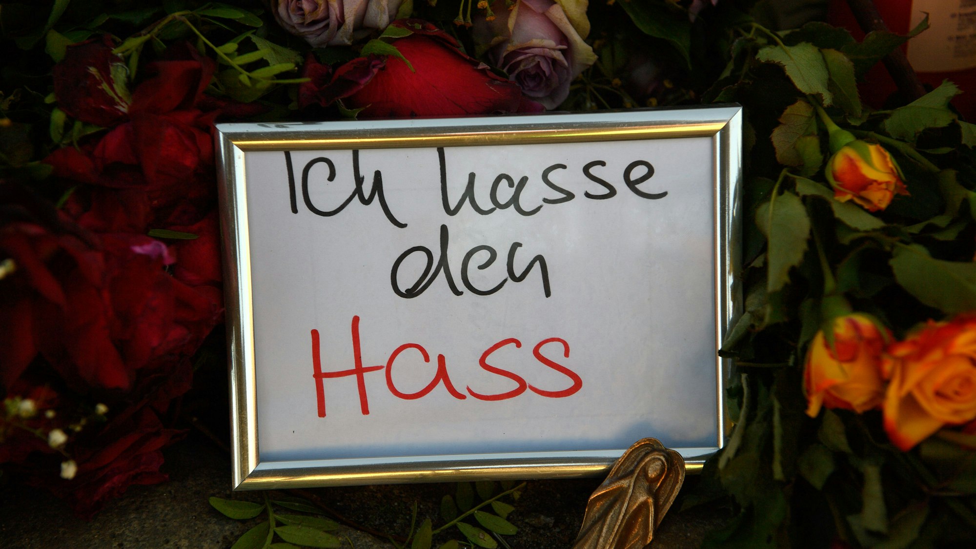 „Ich hasse den Hass“ ist am Gedenkort vor der Johanniskirche auf einem Zettel zu lesen der gerahmt in Mitten von Blumen und Kerzen steht.