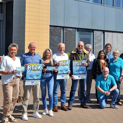 Eine Gruppe Menschen steht, zum Teil in türkisblauen Poloshirts gekleidet, vor dem Mechernicher Rathaus.