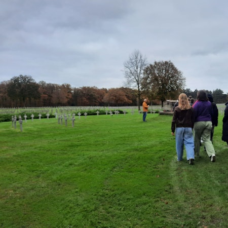 Schülerinnen laufen über eine Kriegsgräberstätte.