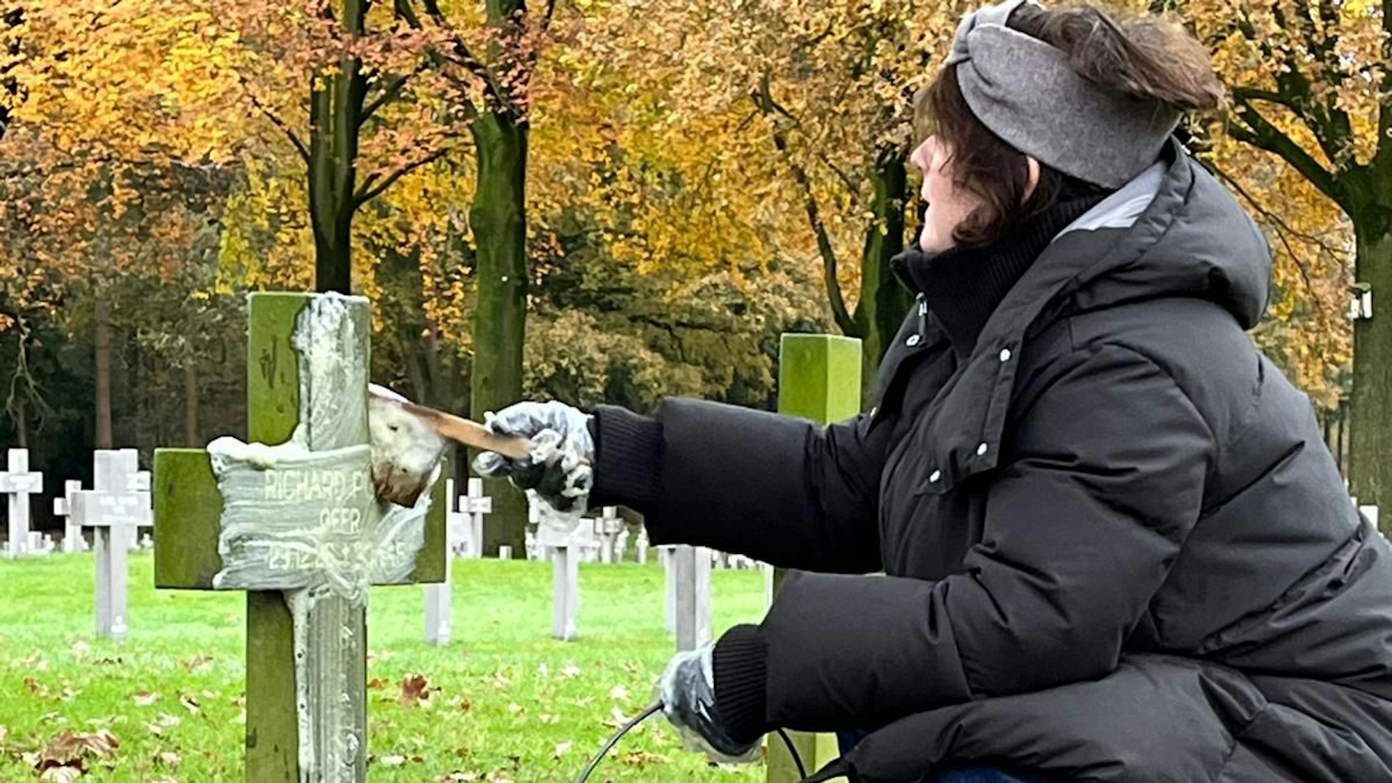 Eine Frau reinigt ein Kreuz.