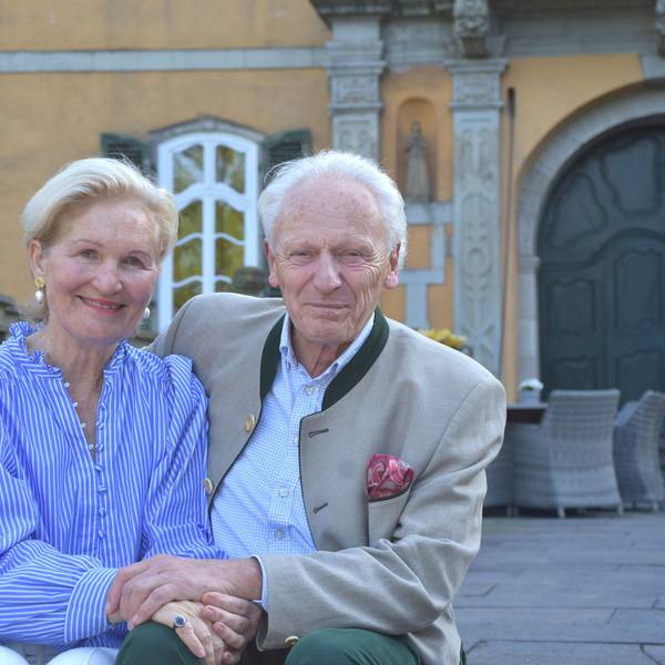 Eine Frau und ein Mann lächeln in die Kamera, er hält sie im Arm.