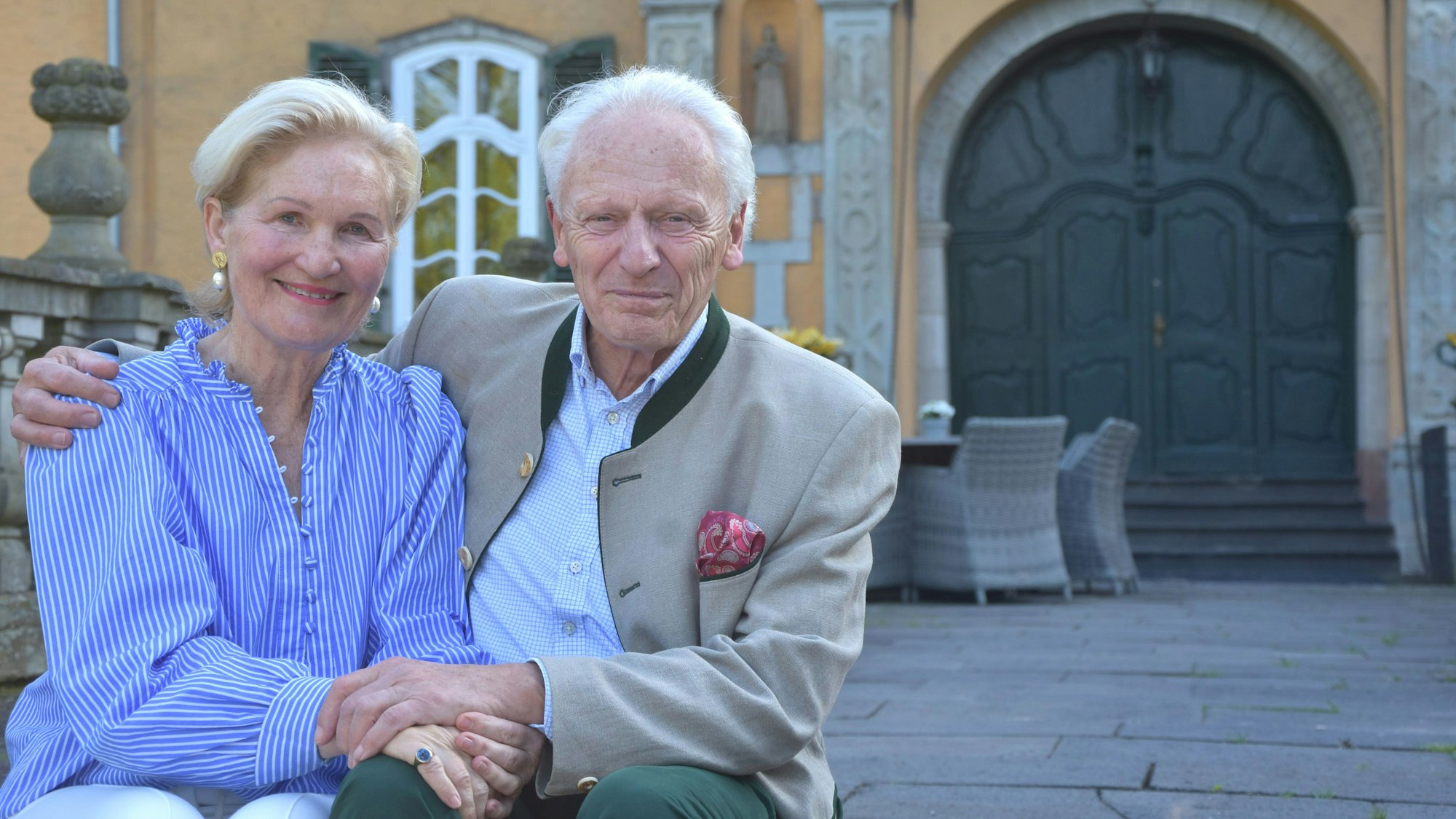 Eine Frau und ein Mann lächeln in die Kamera, er hält sie im Arm.