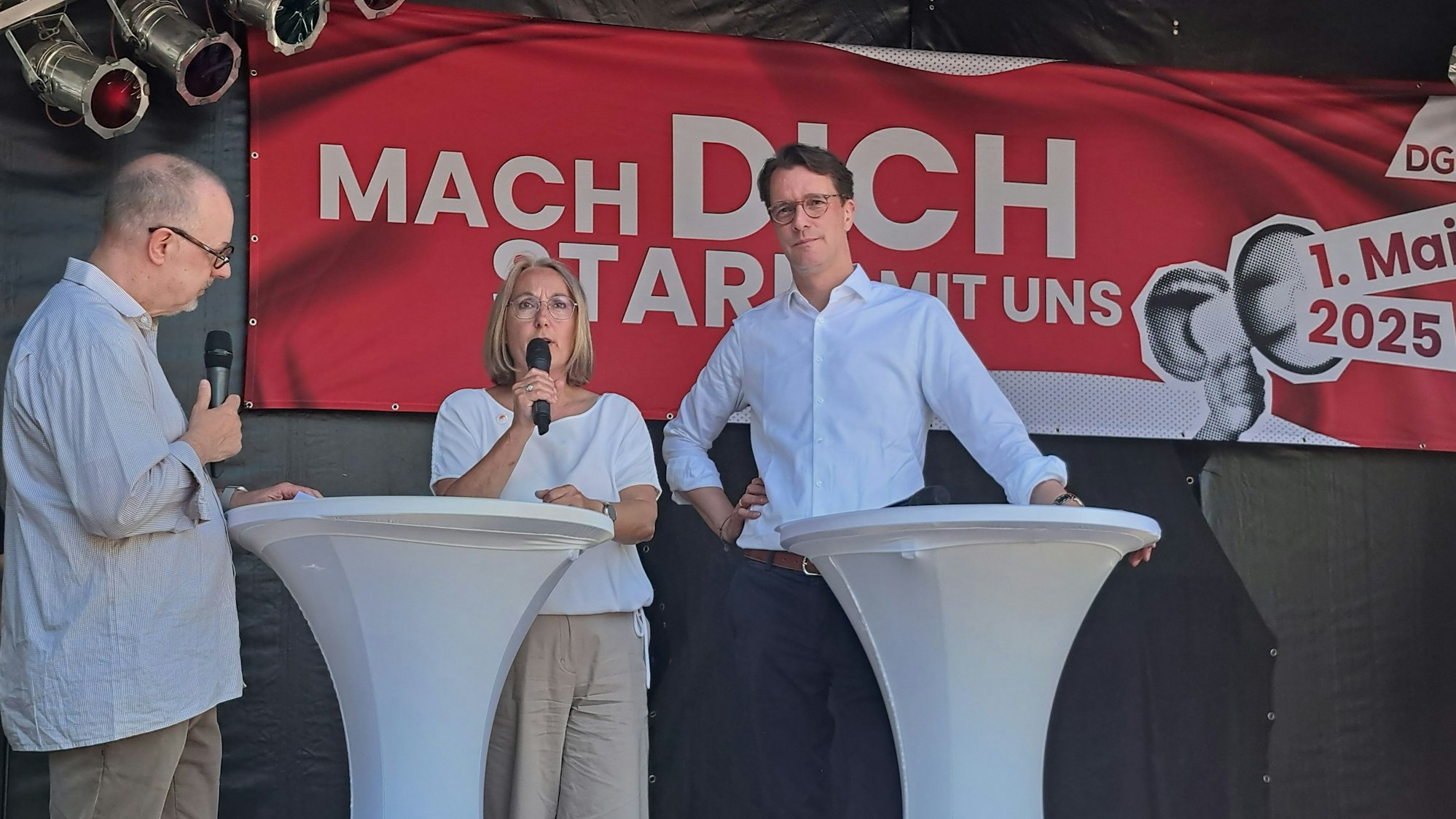 Ministerpräsident Hendrik Wüst, die DGB-Vorsitzende Anja Weber und Moderator Tom Hegermann (v.l.) bei der zentralen Kundegbung des DGB NRW zum Tag der Arbeit in Siegburg.