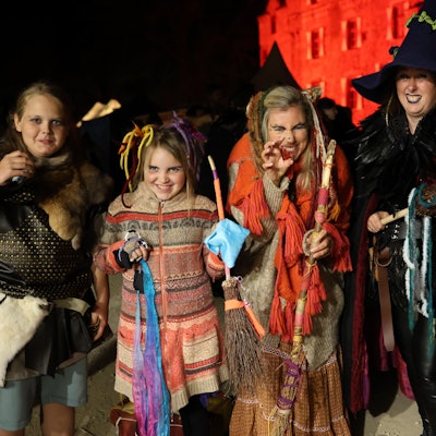 Das Bild zeigt eine Besuchergruppe vor der Burg Satzvey. Die Frauen und Mädchen sind als Hexen verkleidet.