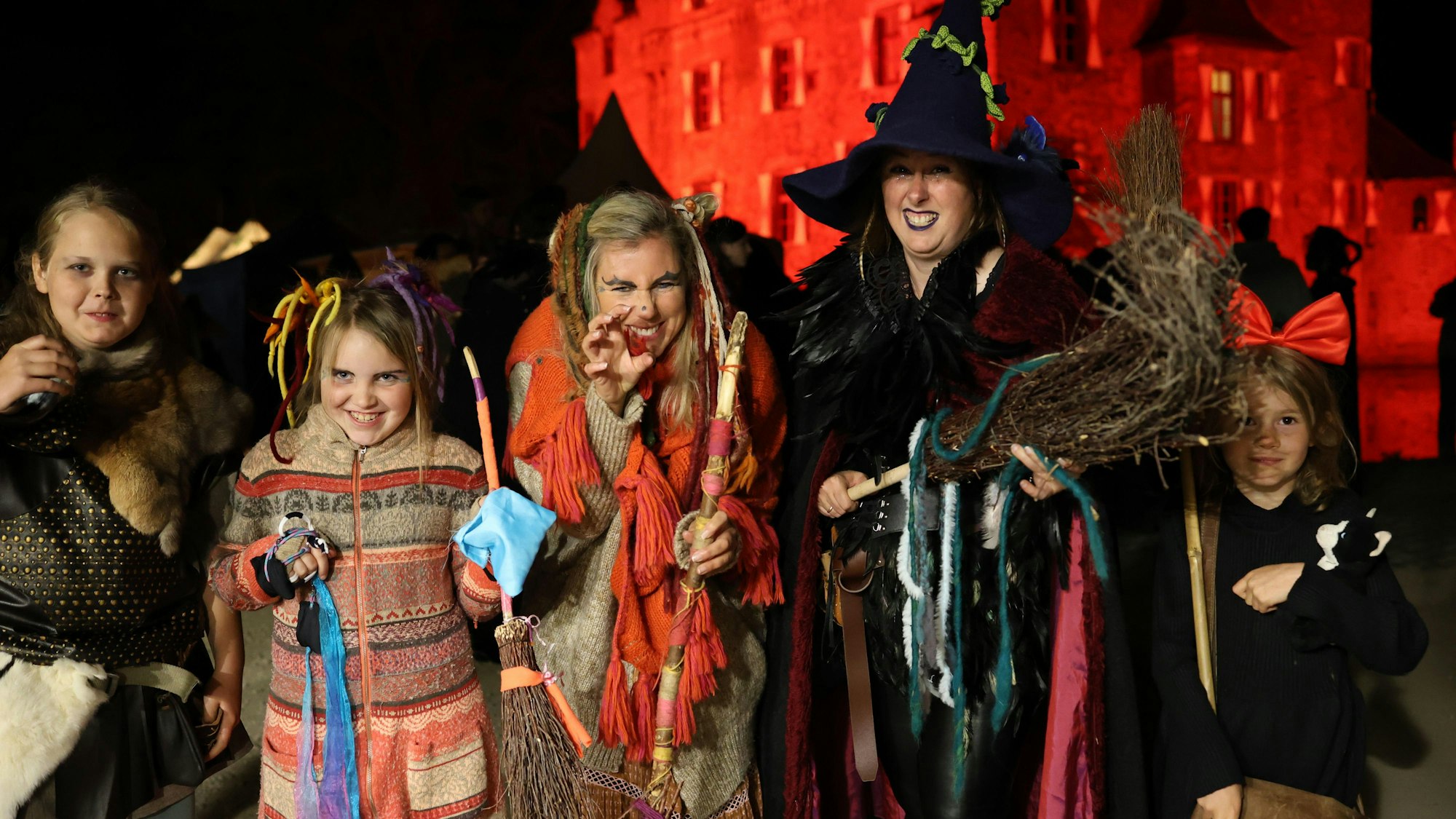 Das Bild zeigt eine Besuchergruppe vor der Burg Satzvey. Die Frauen und Mädchen sind als Hexen verkleidet.