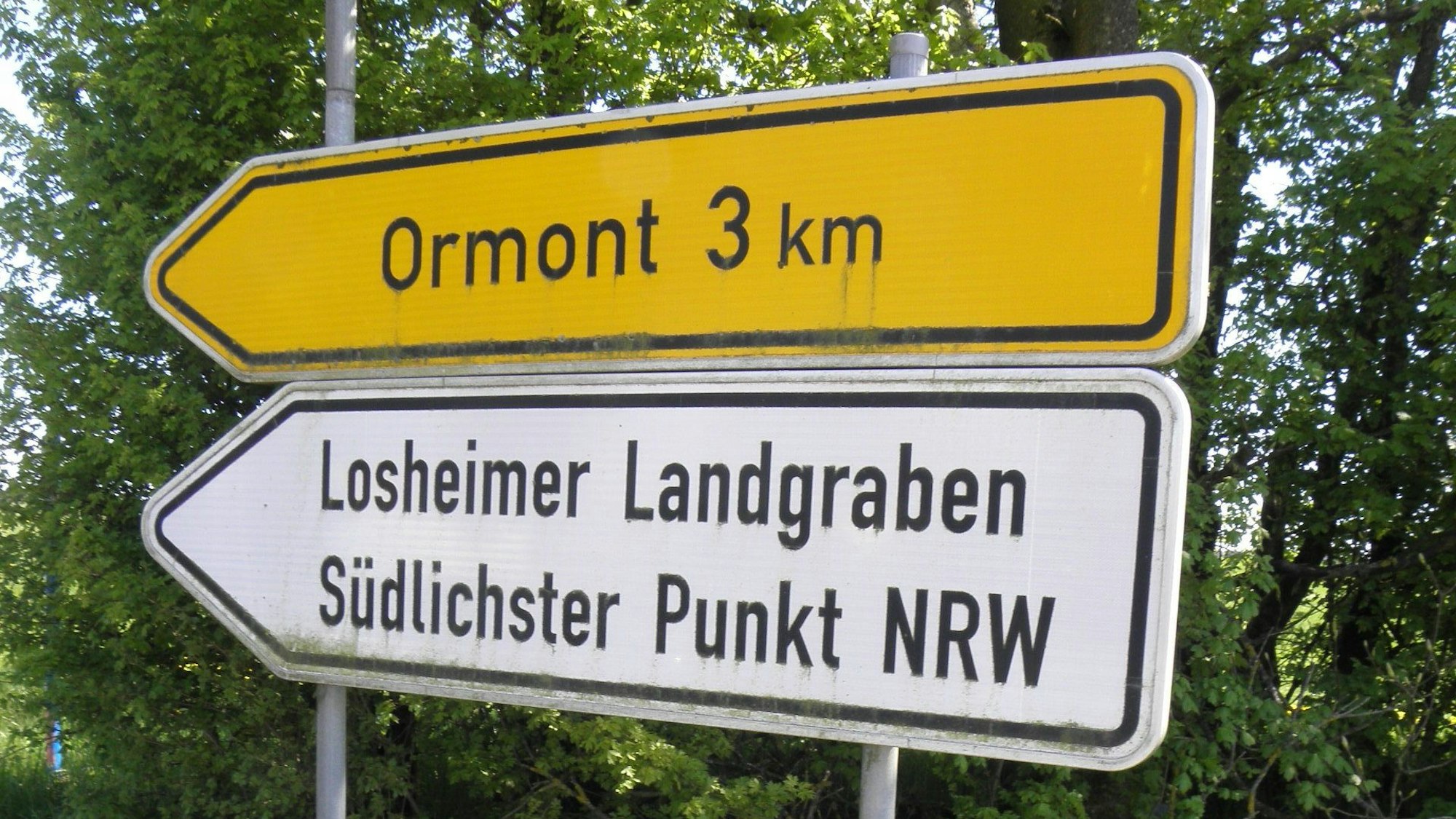 Zwei Straßenschilder weisen auf den drei Kilometer entfernten Ort Ormont hin und auf den Losheimer Landgraben, den südlichsten Punkt von NRW.