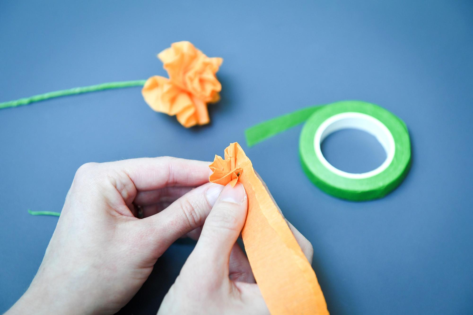 Das Krepppapier nicht zu eng um den Basteldraht wickeln - wenn dabei kleine Falten entstehen, wirkt die Blume am Ende realistischer.