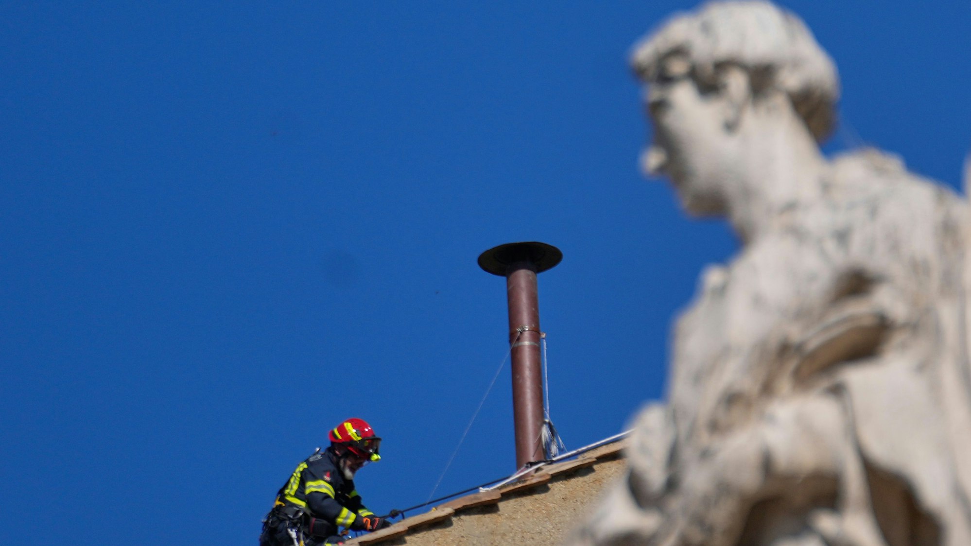 Feuerwehrleute platzieren den Schornstein auf dem Dach der Sixtinischen Kapelle, wo sich die Kardinäle zur Wahl des neuen Papstes versammeln werden.