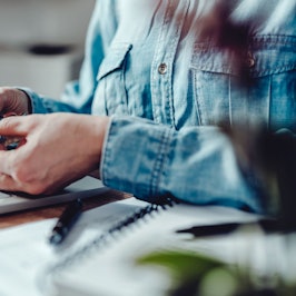 Eine Frau sitzt vor dem Laptop im Home Office und nimmt Tabletten.