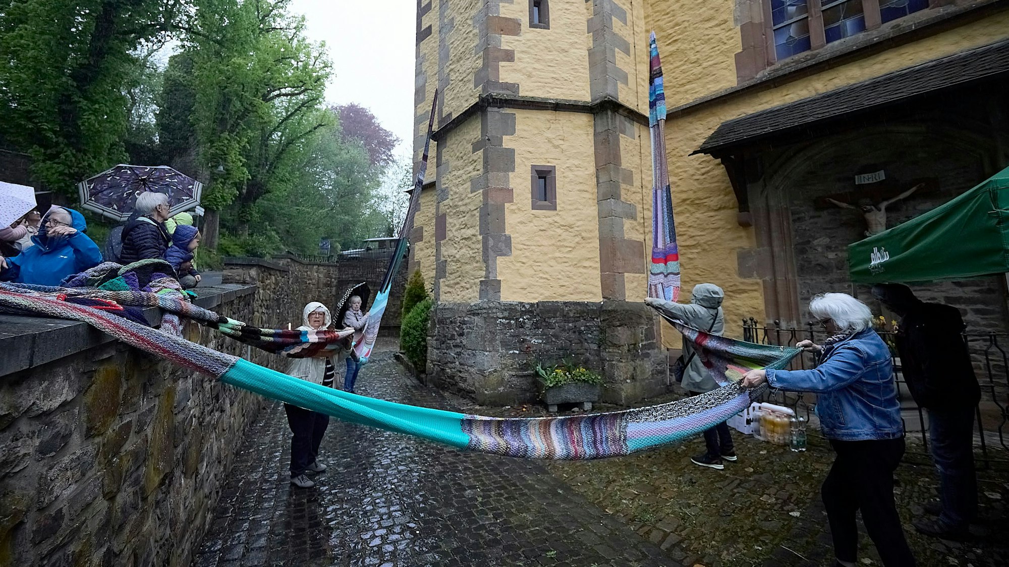Einige Menschen stehen vor der Kirche und breiten den langen Wollschal aus.
