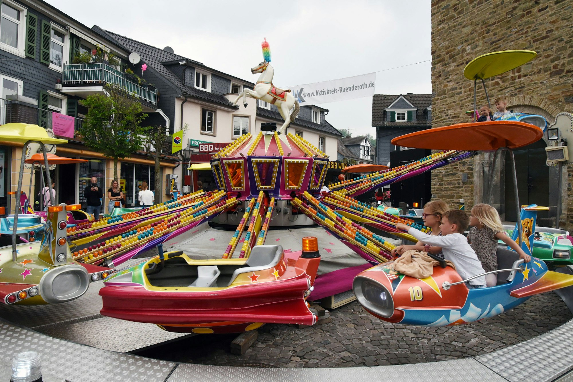 Das Foto zeigt ein Fahrgeschäft mit drei Kindern.