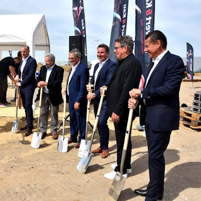 Das Bild zeigt Männer mit Anzügen, die Spaten in der Hand halten.