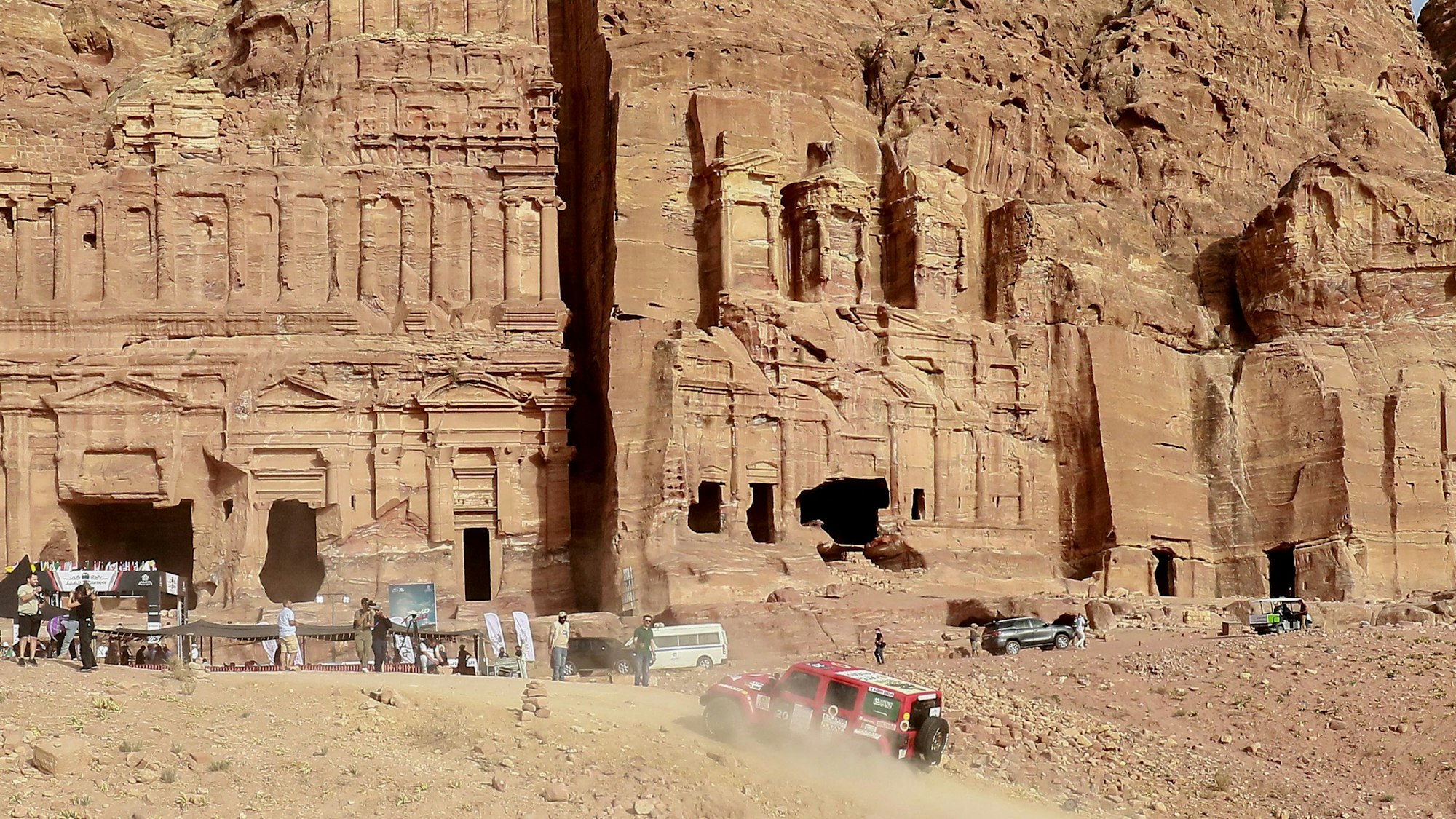 Ein Rallye-Auto fährt an den Felsen der Stadt Petra vorbei.