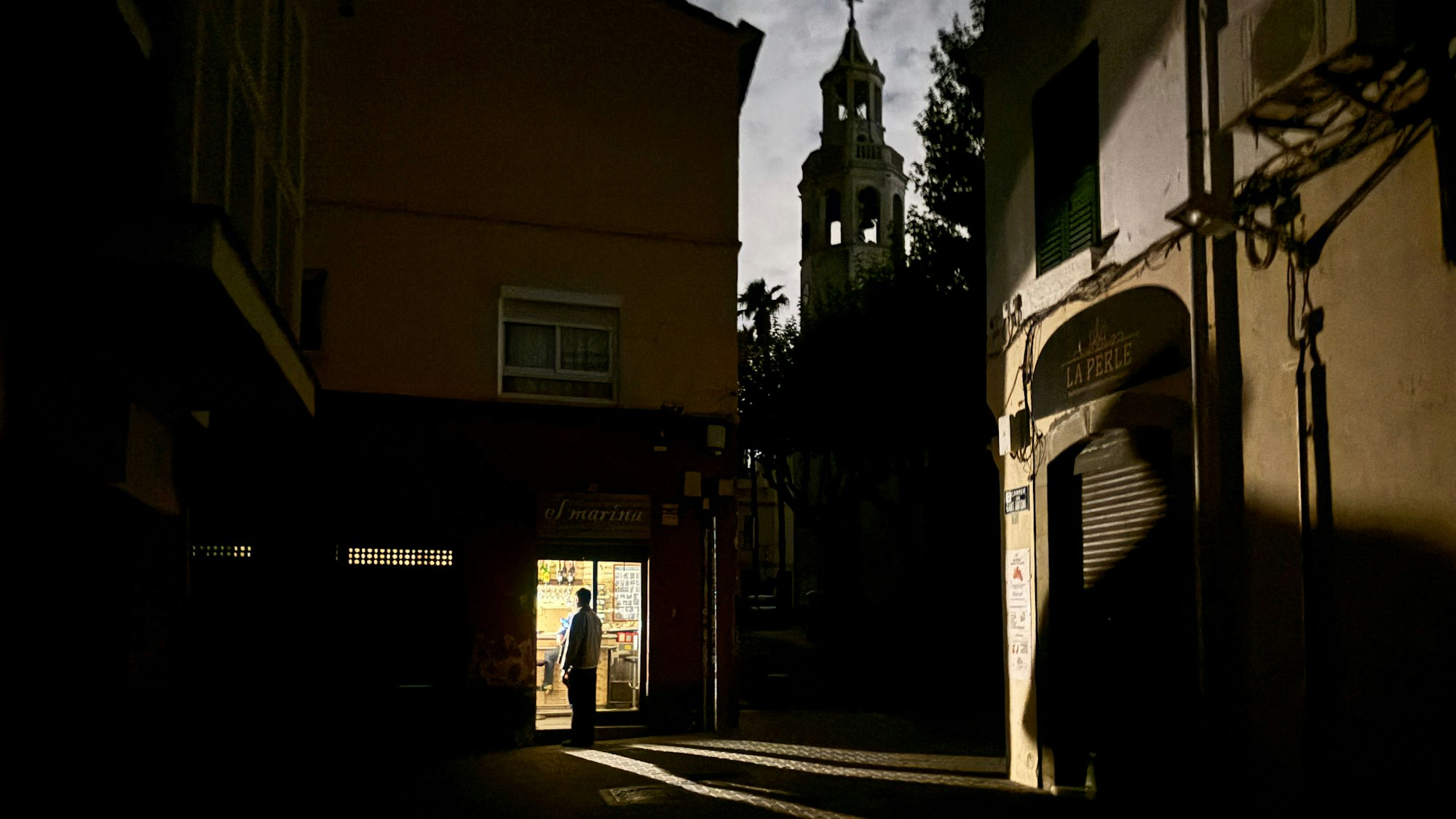Spanien, Premià de Mar: Ein Mann steht bei einem Stromausfall in einer von einer Campinglampe erleuchteten Eckkneipe an der Placa de l'Ajuntament in der Kleinstadt Premià de Mar bei Barcelona.