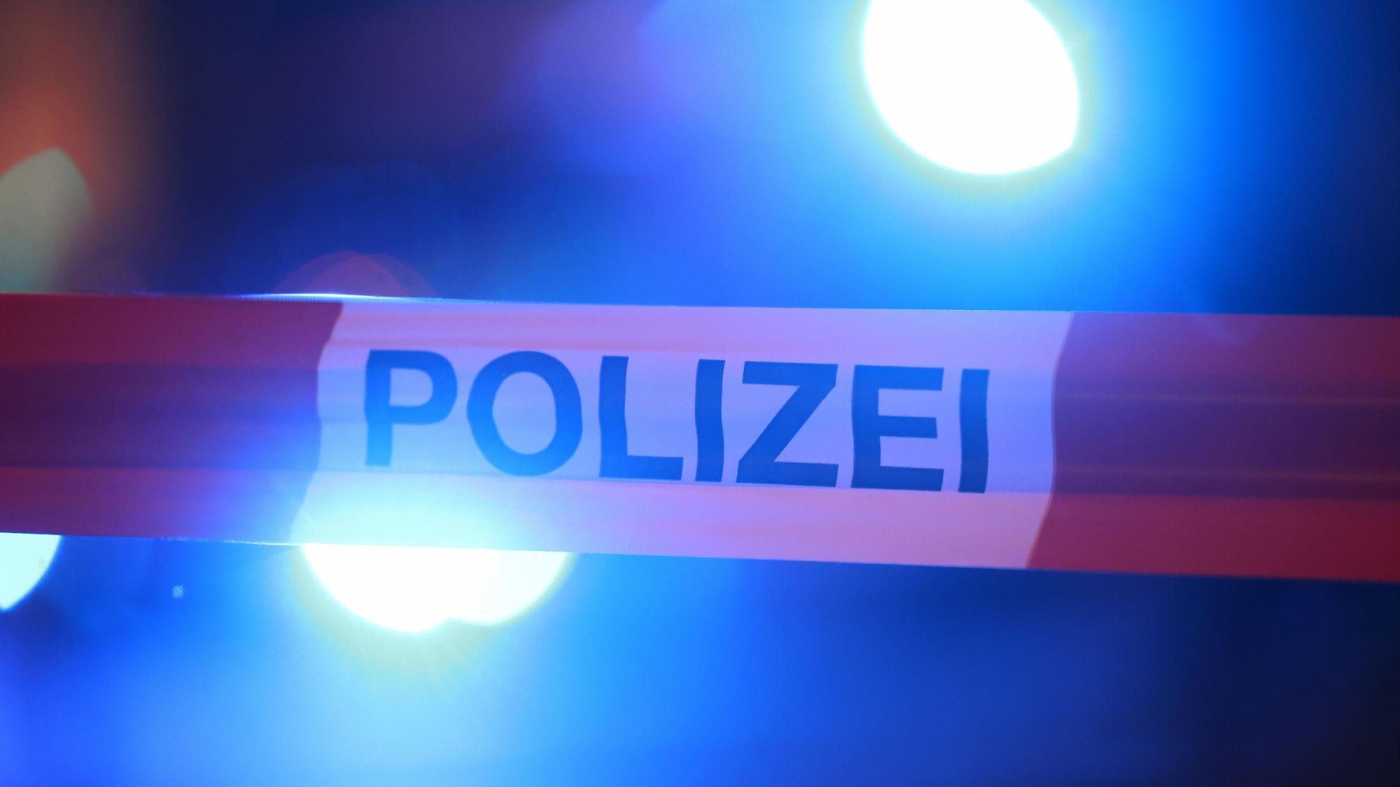 Blaulichter leuchten hinter einem Absperrband der Polizei.