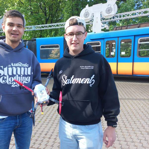 Zwei junge Männer halten eine Drohne in den Händen.