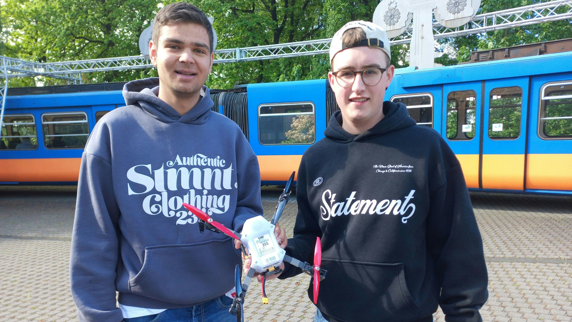 Zwei junge Männer halten eine Drohne in den Händen.