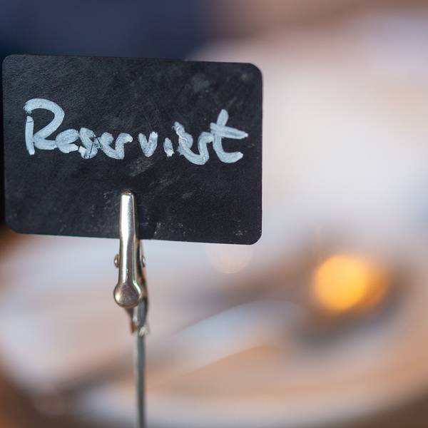 Eine Tafel mit der Aufschrift „Reserviert“ steht auf einem gedeckten Tisch.