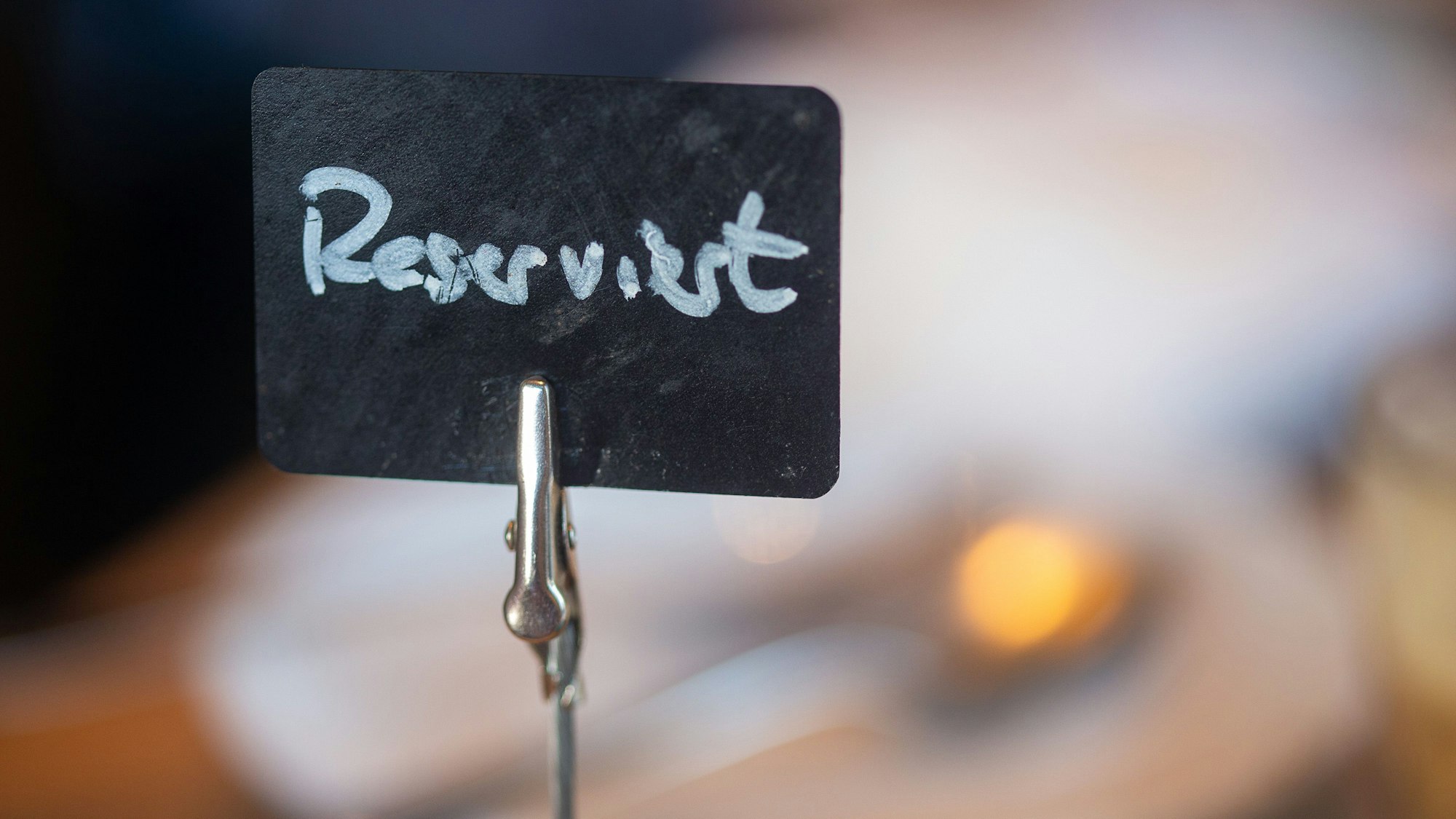 Eine Tafel mit der Aufschrift „Reserviert“ steht auf einem gedeckten Tisch.