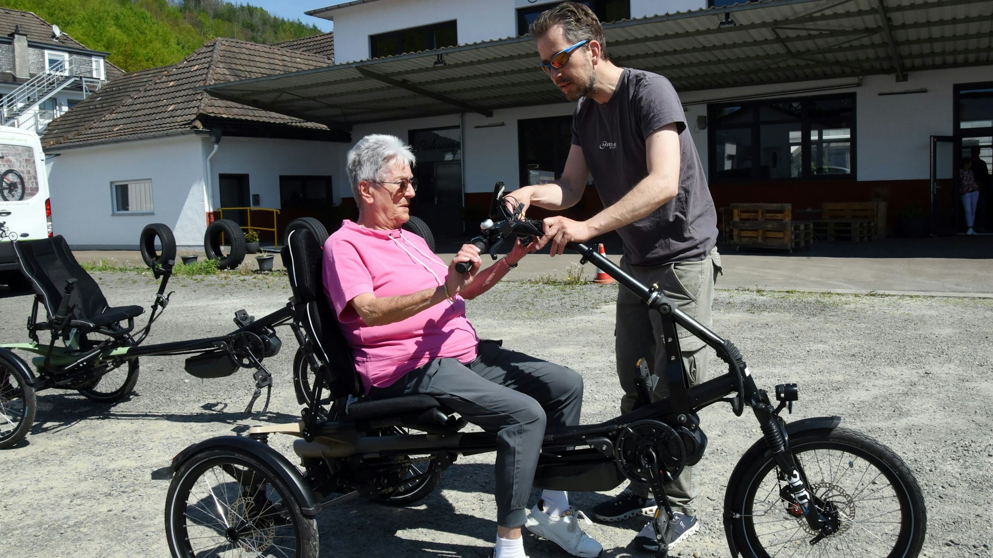 Ein Mann erklärt einer Frau die Handhabung eines Inklusions-Fahrrads.