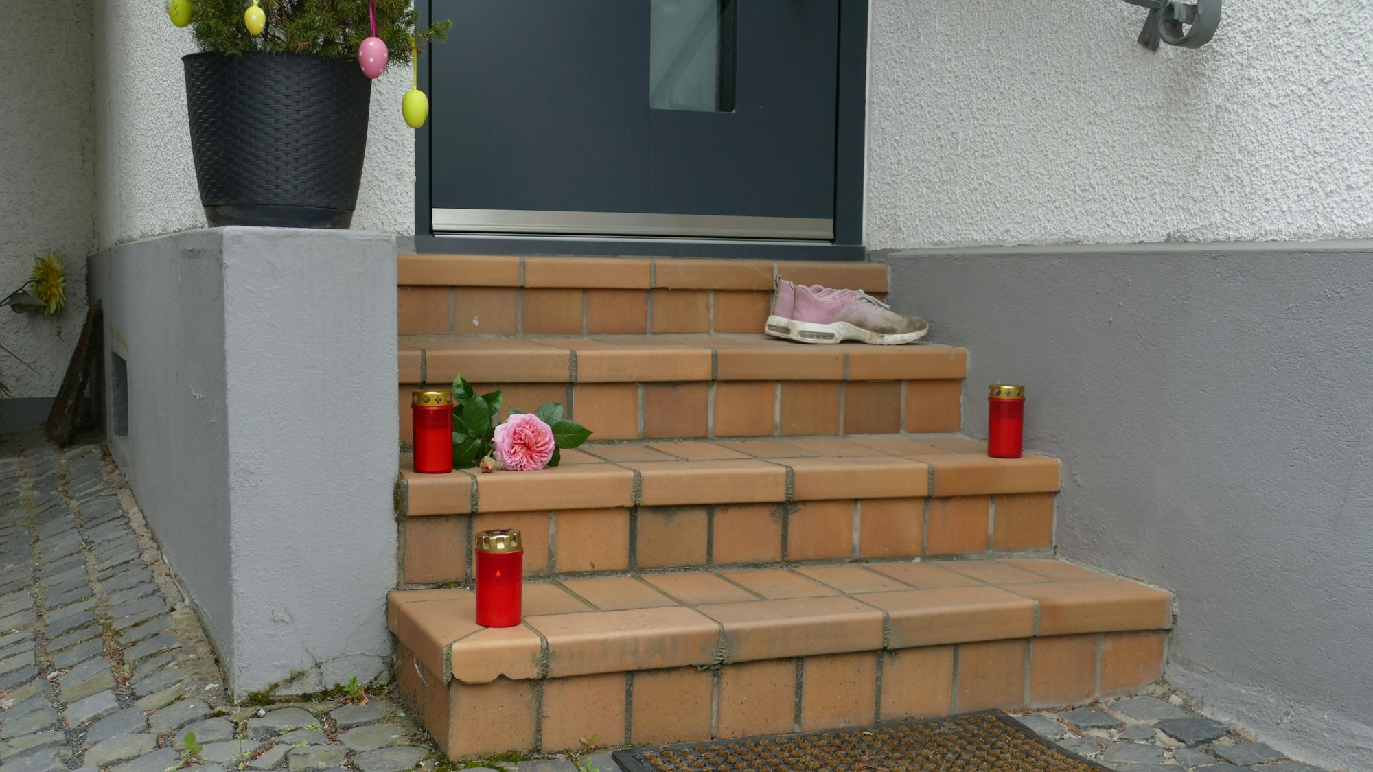 Kerzen stehen vor dem Haus, in dem eine 30-Jährige getötet wurde.