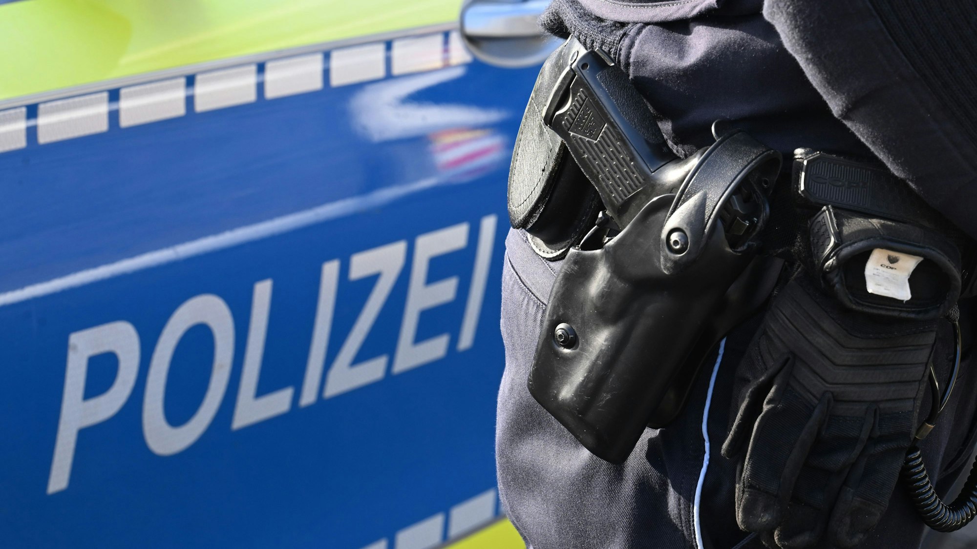 Das Foto zeigt einen Beamten vor einem Polizeiauto.