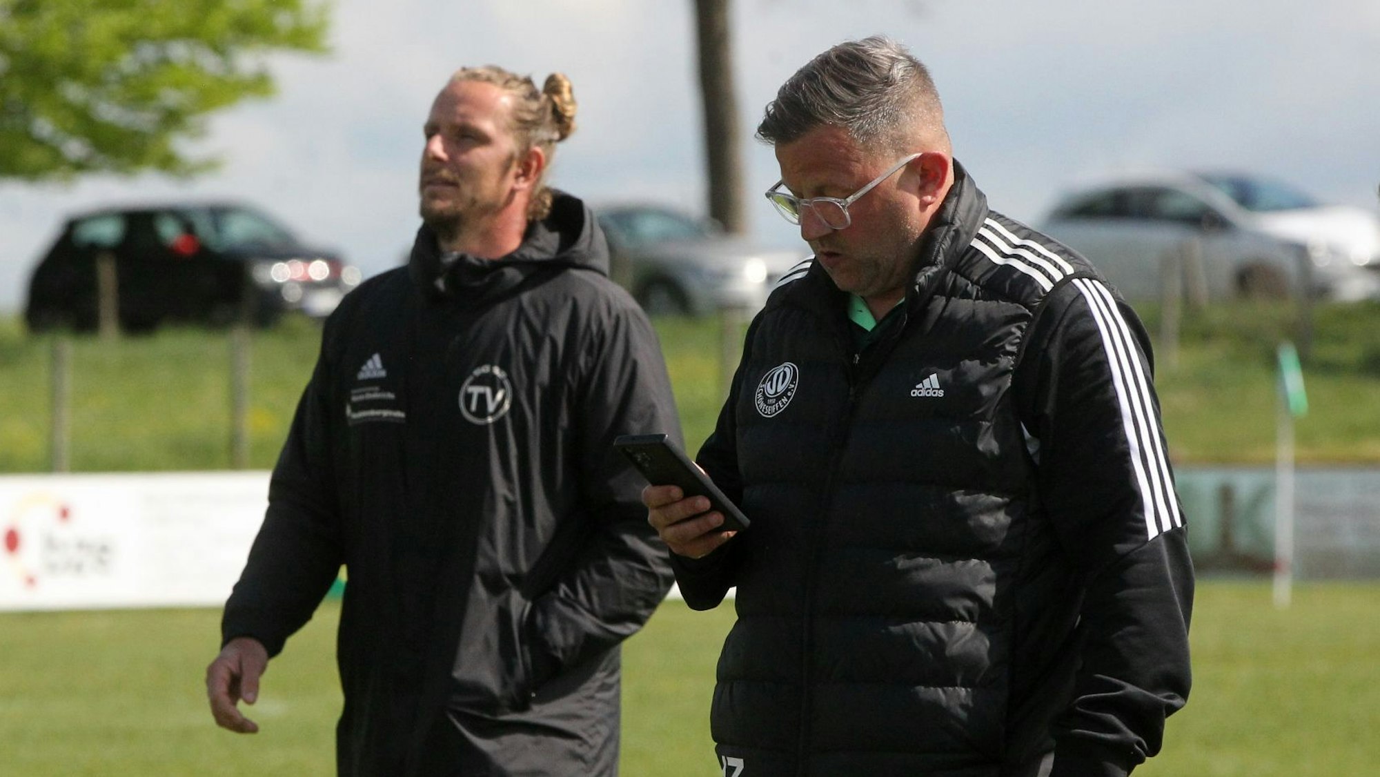 Die beiden Trainer nebeneinander: Heiko Zimmer wirft einen Blick auf sein Handy.