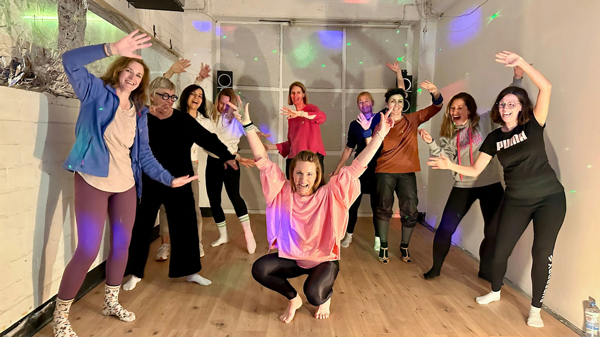 Eine Gruppe Frauen posiert in einem Kellerraum, alle haben sichtbar Spaß.