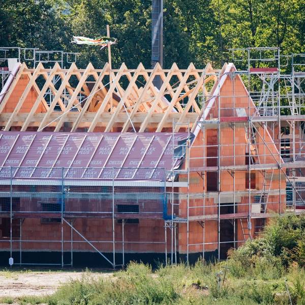 Ein Richtkranz weht am Dachstuhl eines neu gebauten Einfamilienhauses in einer Neubausiedlung.