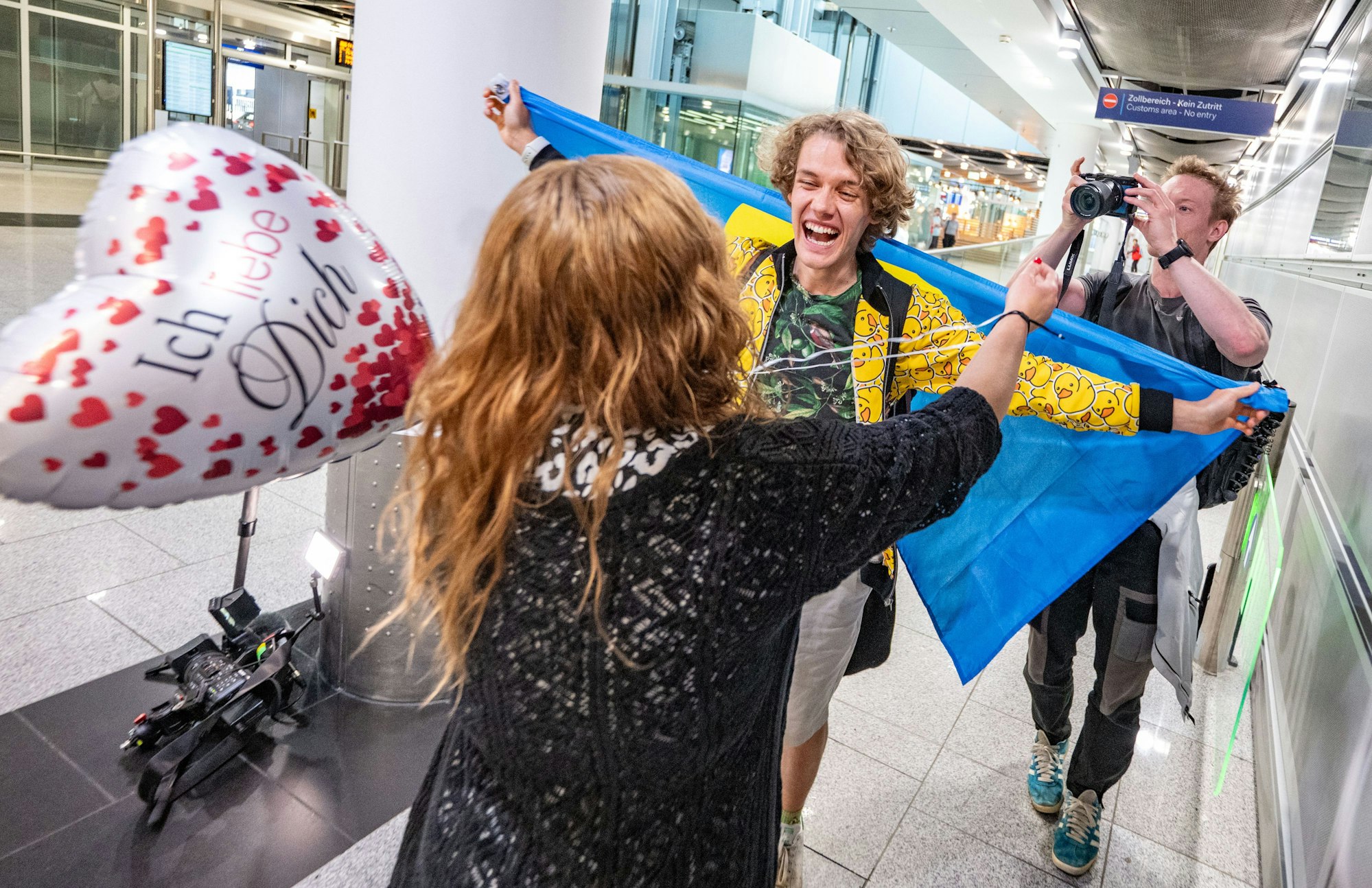 Düsseldorf: Eingehüllt in die Fahne von Palau wird Reiseinfluencer Luca Pferdmenges nach seiner XXL-Reise von seiner Mutter am Flughafen Düsseldorf begrüßt.