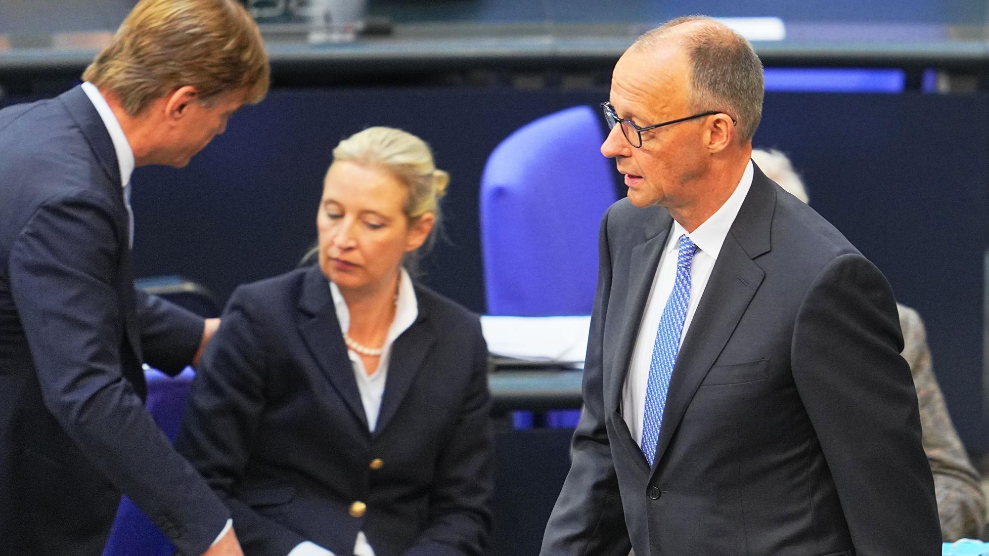 Friedrich Merz geht am Dienstag durch den Bundestag. Im Hintergrund ist AfD-Chefin Alice Weidel zu sehen.