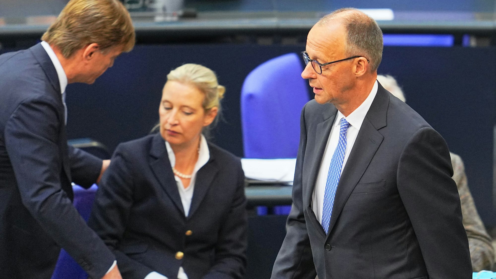 Friedrich Merz geht am Dienstag durch den Bundestag. Im Hintergrund ist AfD-Chefin Alice Weidel zu sehen.