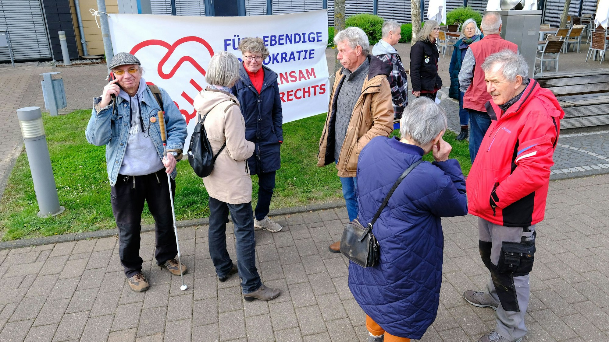 Frauen und Männer haben sich vor einem Banner am Rathaus in Mechernich versammelt.