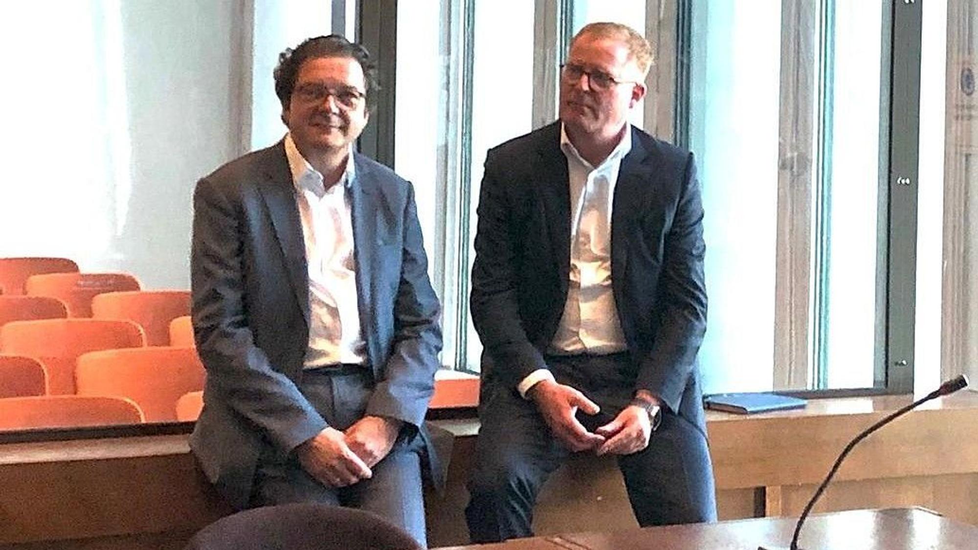 Auf dem Foto sind zwei Männer in einem Gerichtssaal zu sehen.
