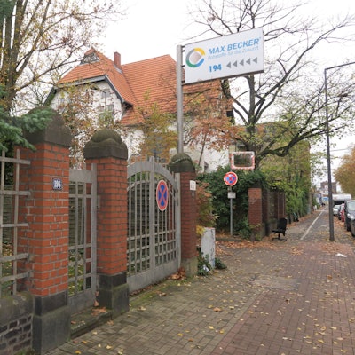 Neben einem Eingangstor aus Stahl und Backstein ist ein Schild auf dem Max Becker Rohstoffe für die Zukunft steht.