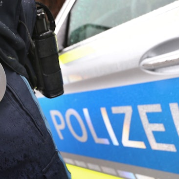 ARCHIV - 15.03.2019, Bayern, Kempten: ILLUSTRATION - Ein Polizist mit Handschellen und einer Pistole am Gürtel steht vor einem Streifenwagen. (zu dpa: «Abschiebehäftling nach Flucht wieder festgenommen») Foto: Karl-Josef Hildenbrand/dpa +++ dpa-Bildfunk +++