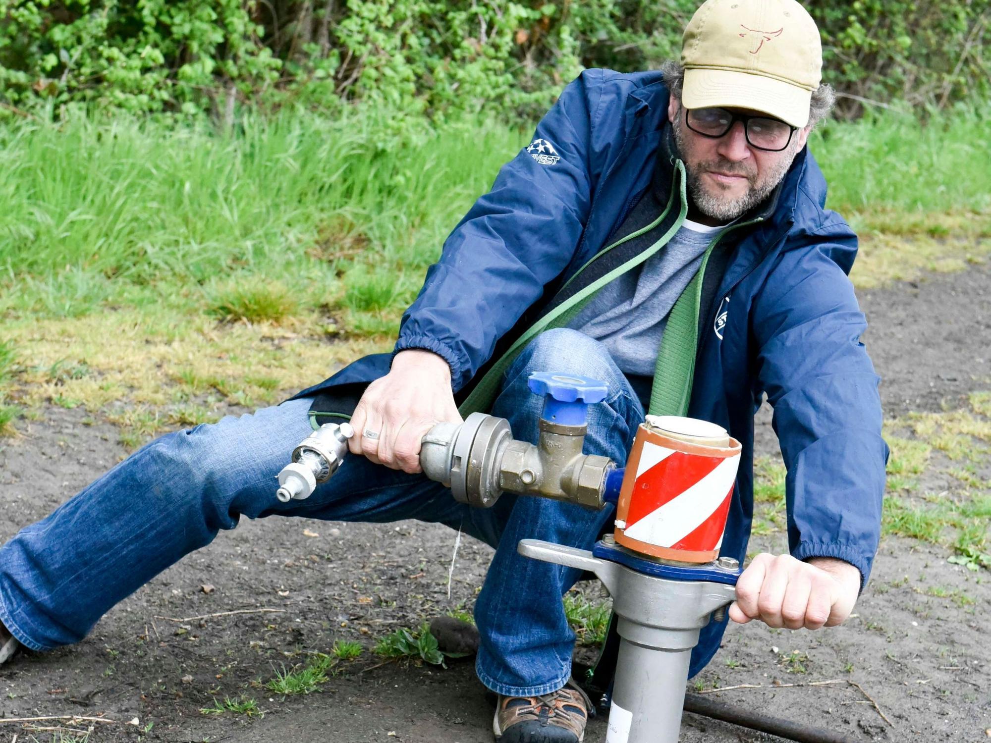 Ein Mann zapft Wasser ab.
