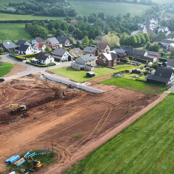 Die Drohnenaufnahme zeigt die Baustelle eines Regenrückhaltebeckens und im Hintergrund den Ort Kallmuth.