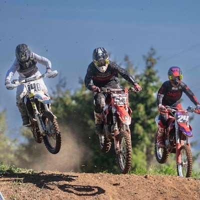 Das Bild zeigt drei Motocrossfahrer während eines Rennens.