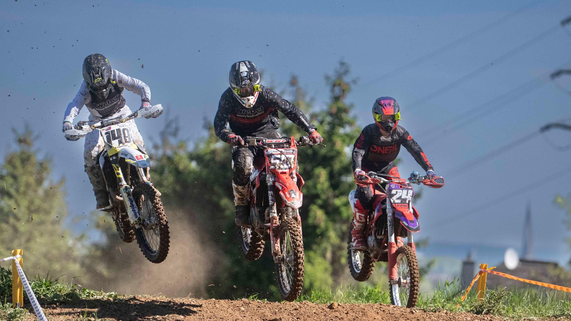 Das Bild zeigt drei Motocrossfahrer während eines Rennens.