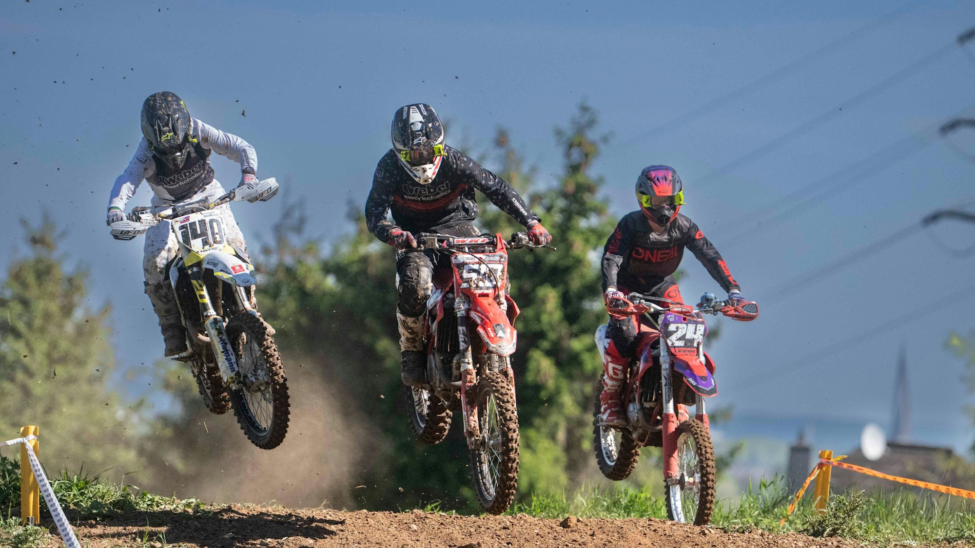 Das Bild zeigt drei Motocrossfahrer während eines Rennens.